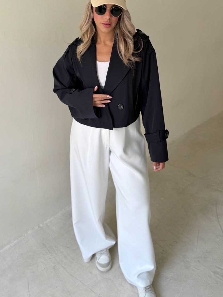 Femme portant la veste trench courte noire avec un pantalon large blanc