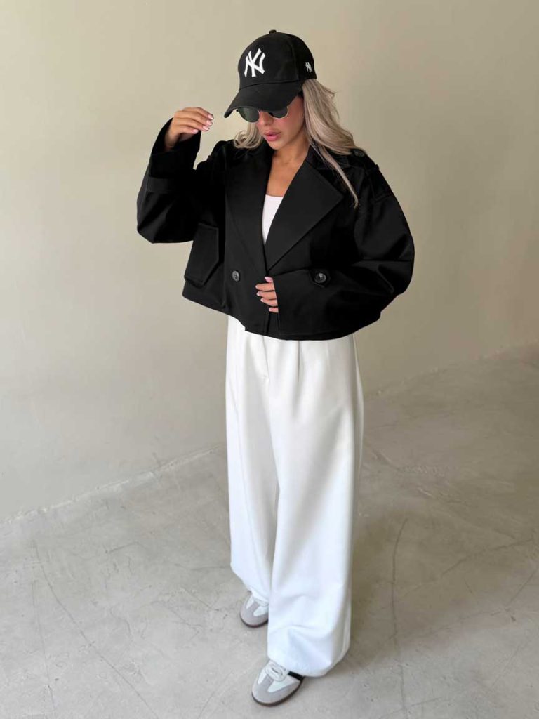 Veste trench courte noire portée avec une casquette