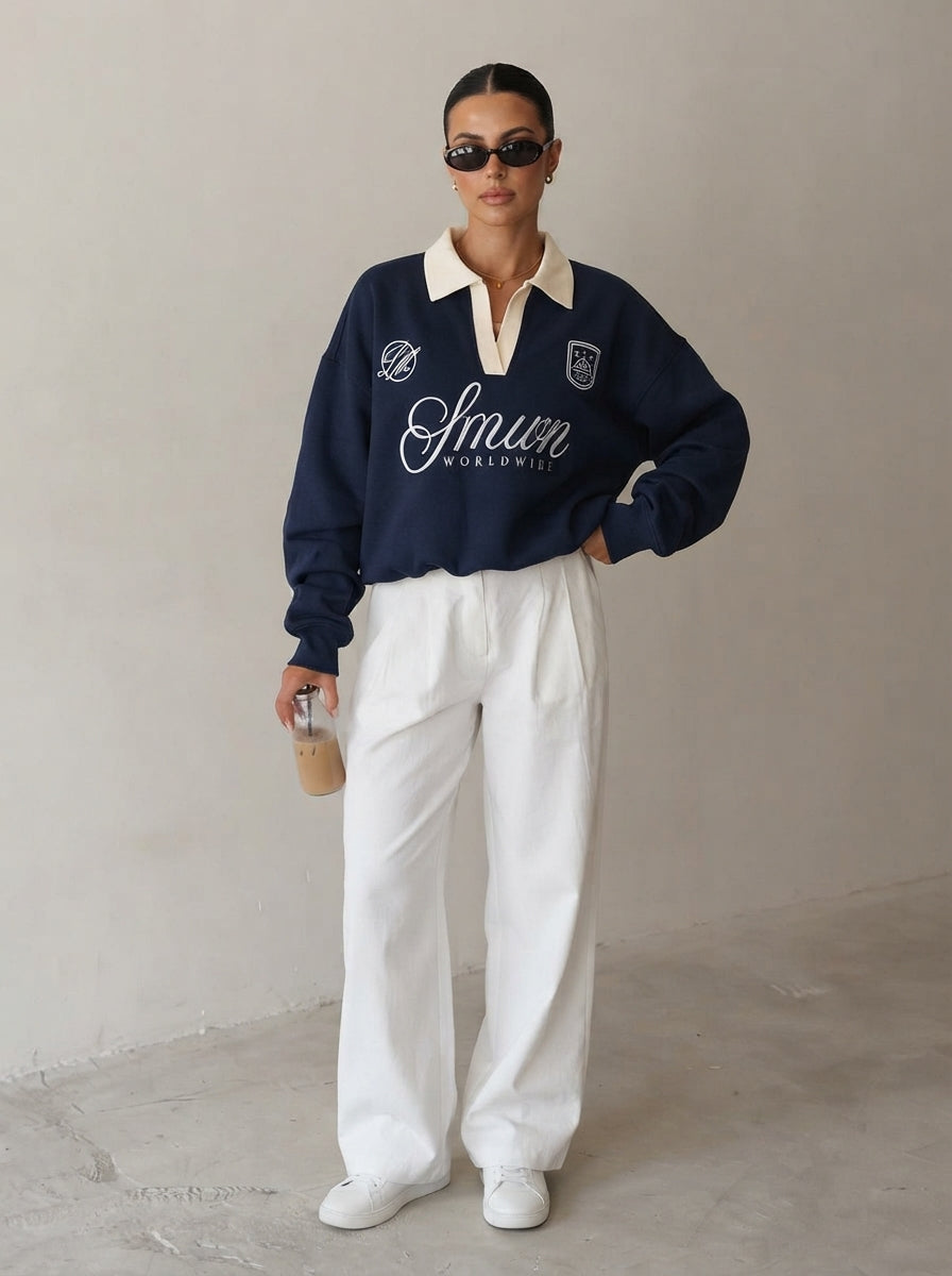 Femme portant le sweat polo brodé bleu marine avec un pantalon large blanc