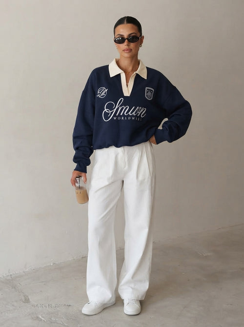 Femme portant le sweat polo brodé bleu marine avec un pantalon large blanc