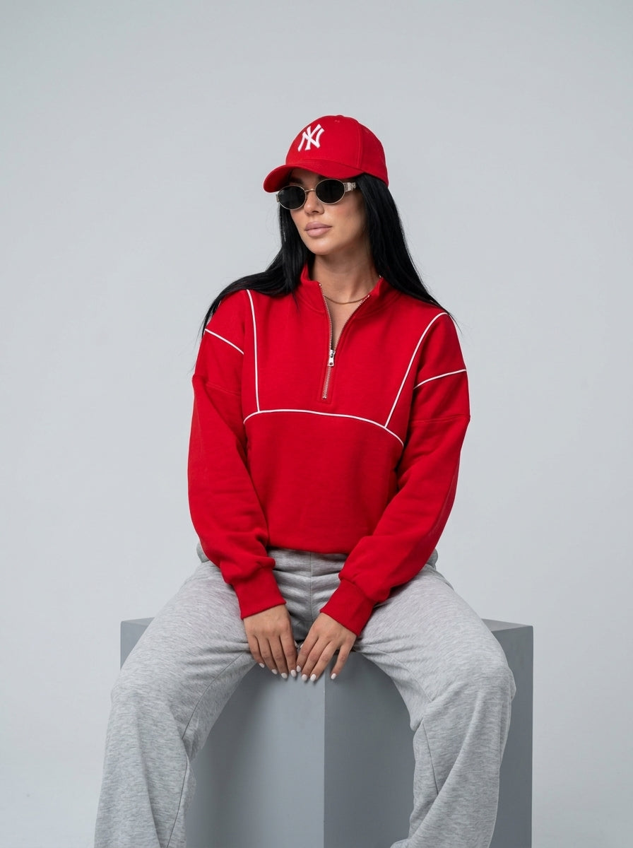 Femme portant le sweat demi-zip rouge à passepoil blanc, assise