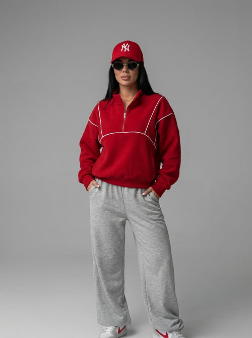Sweat demi-zip rouge à passepoil blanc porté avec un jogging gris