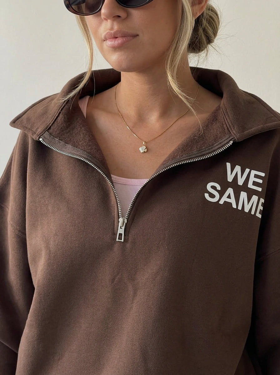 Gros plan du col rabattu et du zip argenté du sweat marron
