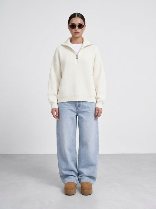 Femme portant le pull demi-zip grosse maille écru avec un jean large