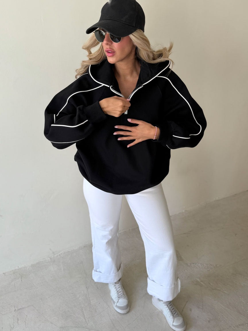Femme qui ajuste le zip du sweat noir à passepoil blanc